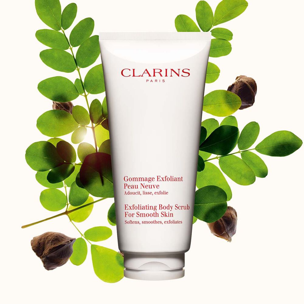 Tube Clarins Gommage Exfoliant Peau Neuve neben Moringa-Samen auf einem beigen Hintergrund